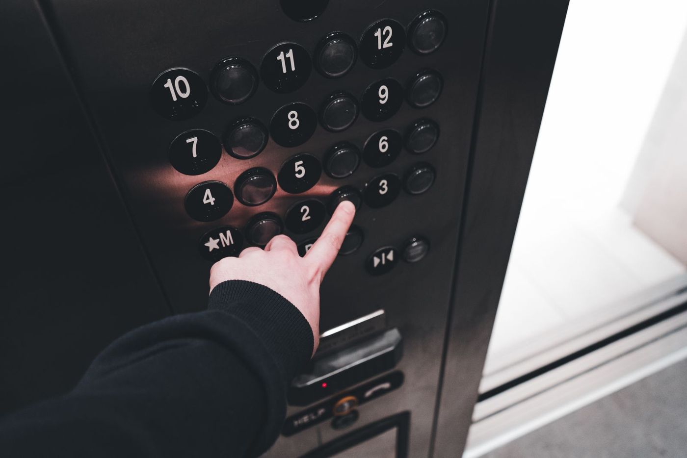 Hand pressing a floor button inside a lift